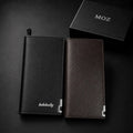 Black and dark brown zip-around wallets standing side by side with MOZ box